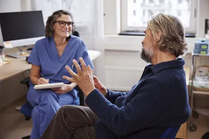 Doctor female smiling_patient man sitting_explaining