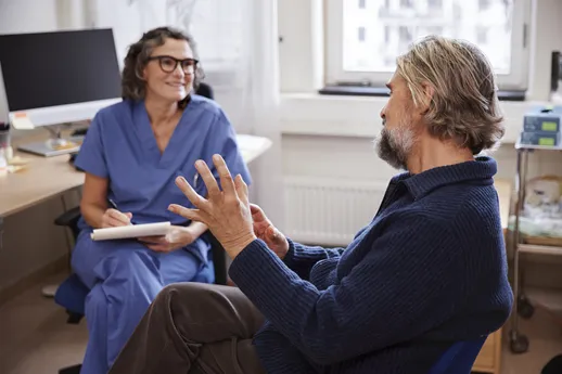 Doctor female smiling_patient man sitting_explaining